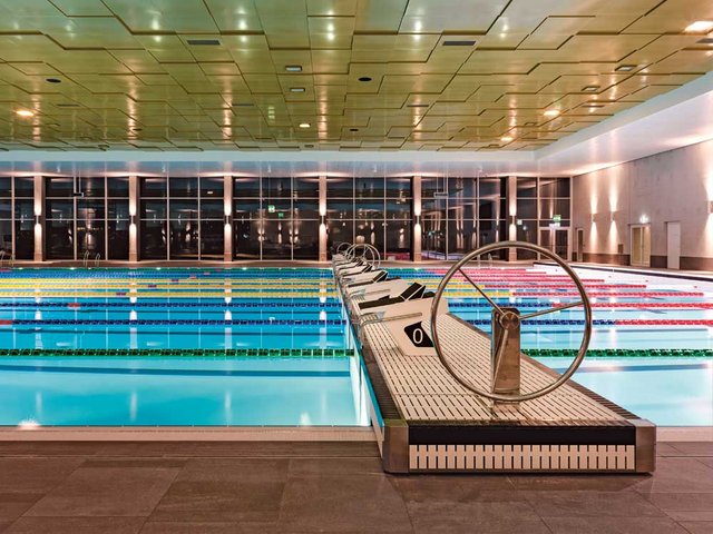 Schwimmvergnügen im Hallenbad Uster. Das Hallentragwerk in Holzbauweise versteckt sich unter der Deckenverkleidung.