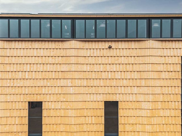 Die Nordfassade des Hochregallagers: Grossformatige Fichtenschindeln verkleiden die Holzstruktur. Darin lagern die Flaschen mit einem alkoholischen Bittergetränk.
