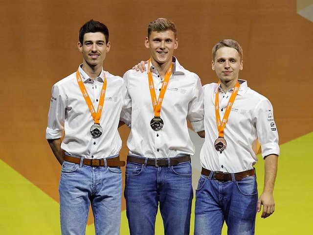Gold für Silvan Aeschlimann! Der Schweizermeister der Zimmerleute auf dem Siegespodest mit dem zweitplatzierten Jules Honoré (l.) und dem drittplatzierten Luca Wissler (r.).
