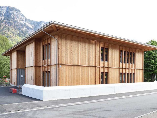 Links befindet sich der Eingang zum Vierfachkindergarten. Durch seine geringe Neigung (8 Grad) wirkt das Walmdach fast wie ein Flachdach.
